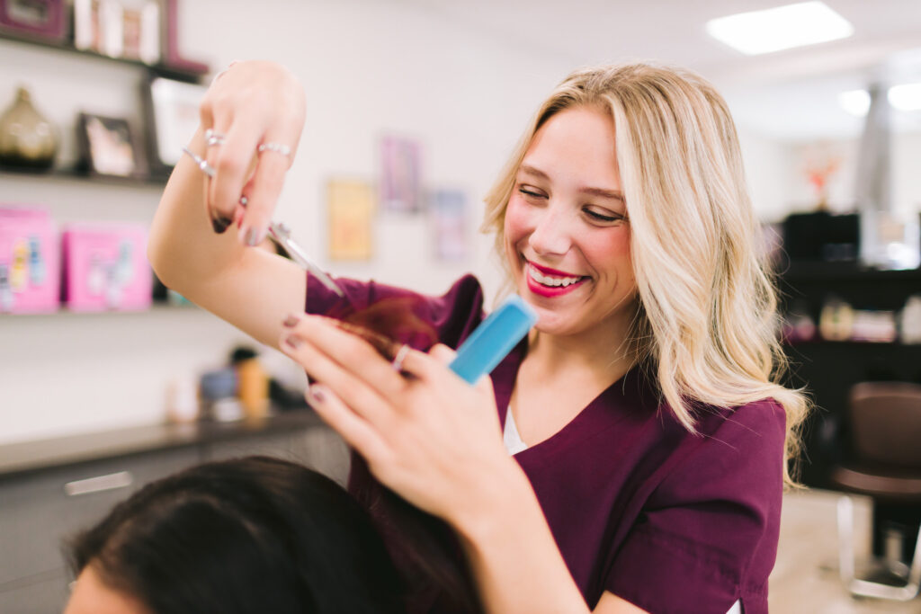 a hairstylist precisely cutting a client's hair during a personal branding session, showcasing her expertise and professionalism.
