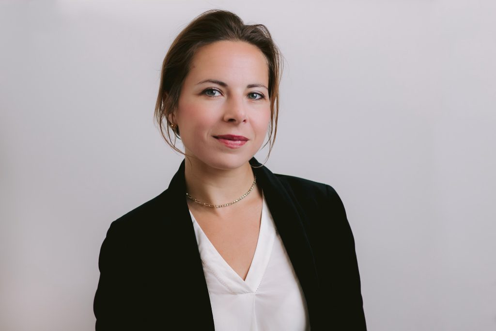 a female professional in a black blazer and white shirt poses for a professional headshot, showcasing her polished and confident look.