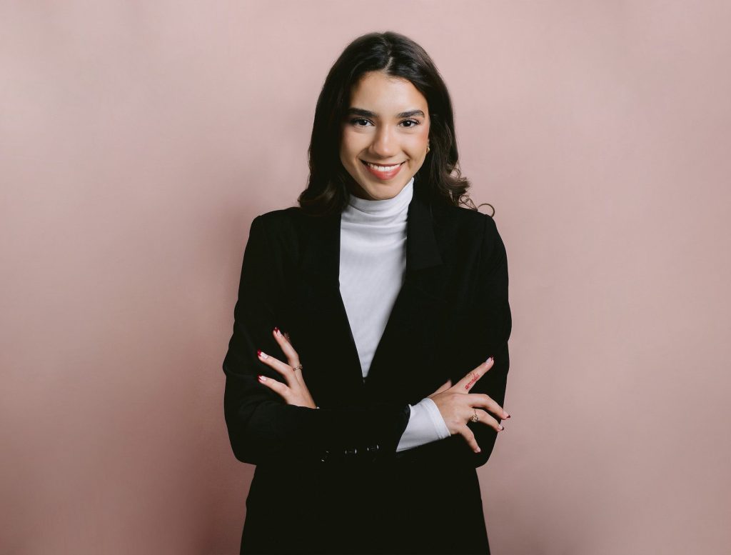 Portrait of a cheerful businesswoman on a pink backdrop, highlighting her personality during a professional photo session.